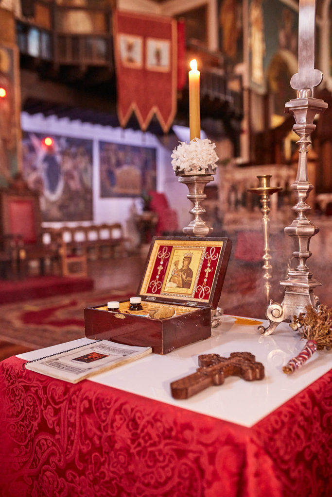 Baptism table with a candle, cross and icon box on a red cloth