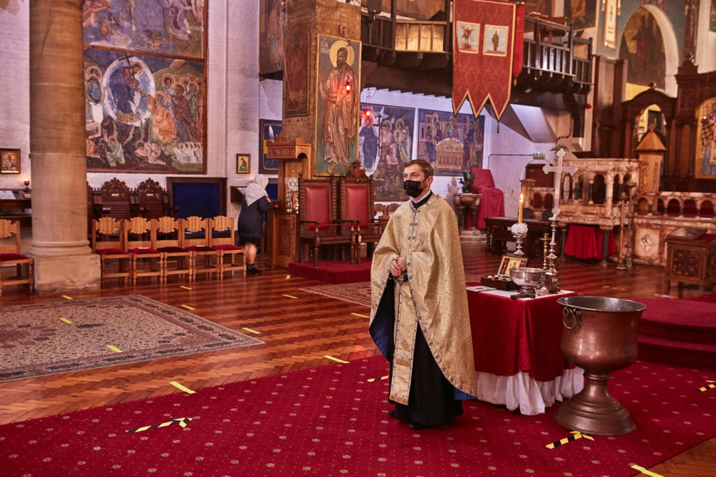 Priest in gold vestments beside the font before the baptism