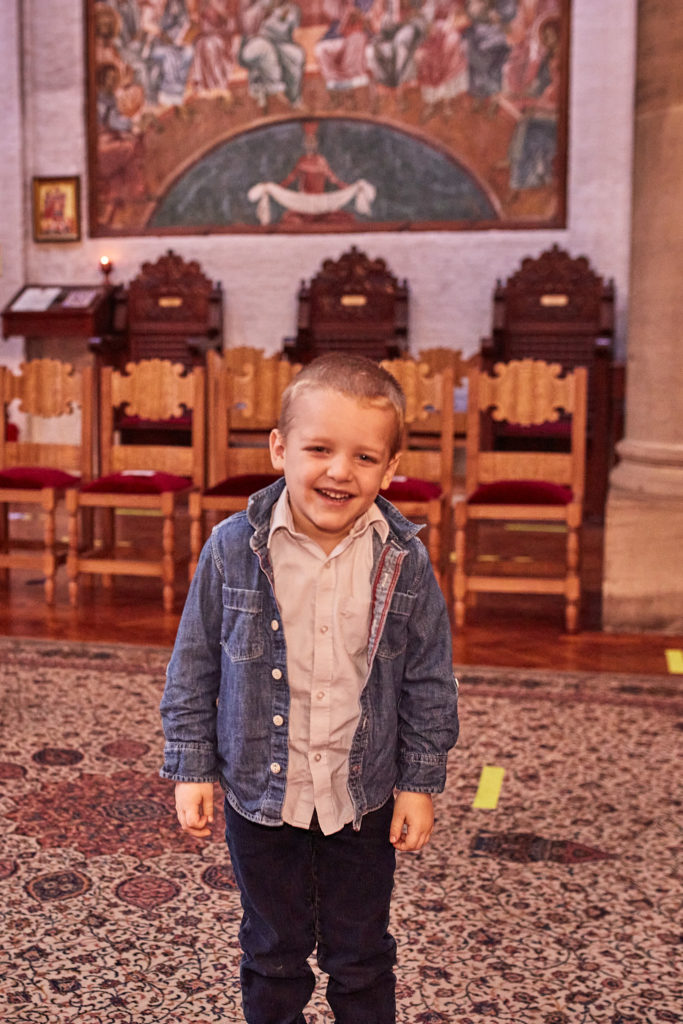 Young boy in a denim jacket laughing inside the church