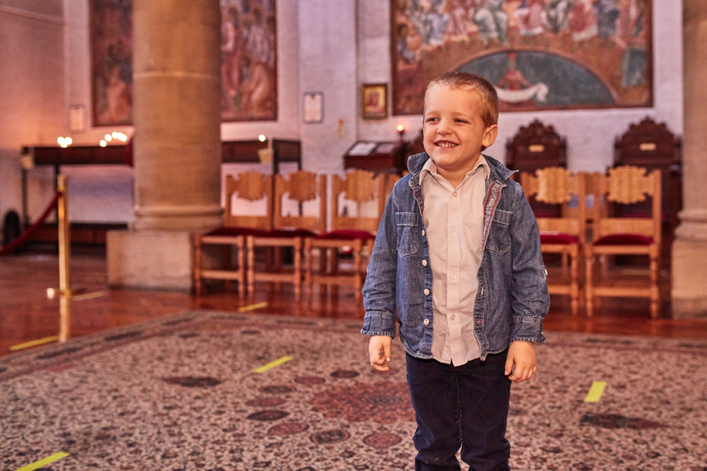 Young boy grinning as he stands on the patterned church carpet