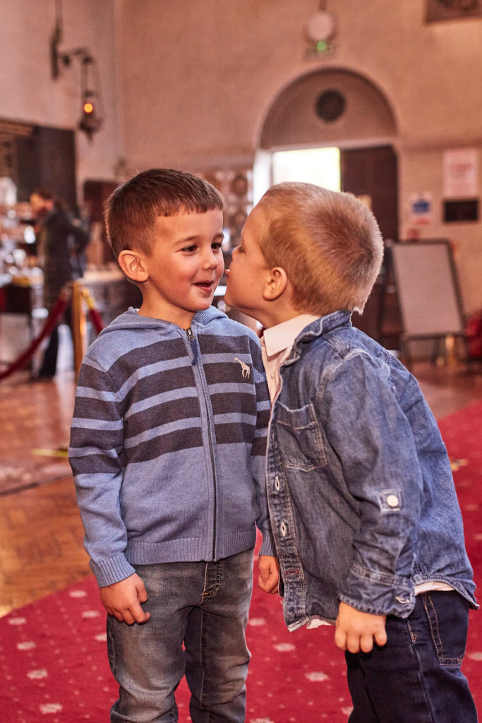 Young boy kissing his friend on the cheek in church