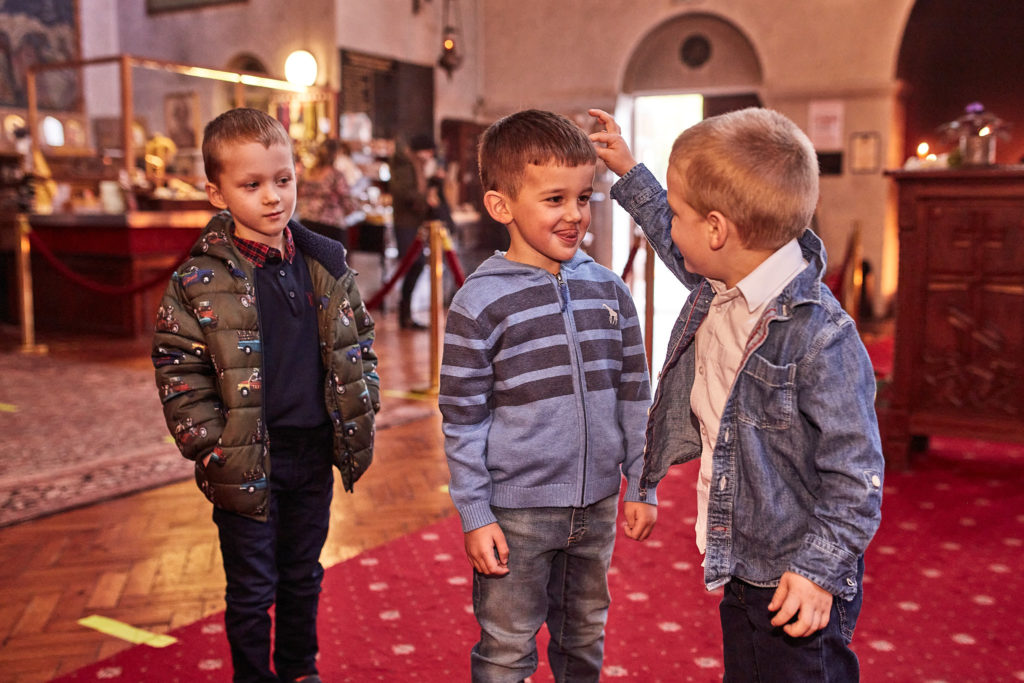Three young boys chatting together on the red carpet in church