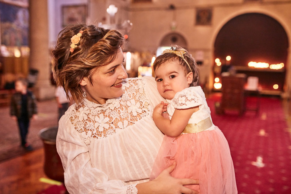 Mother holding her daughter in a pink tutu after the baptism
