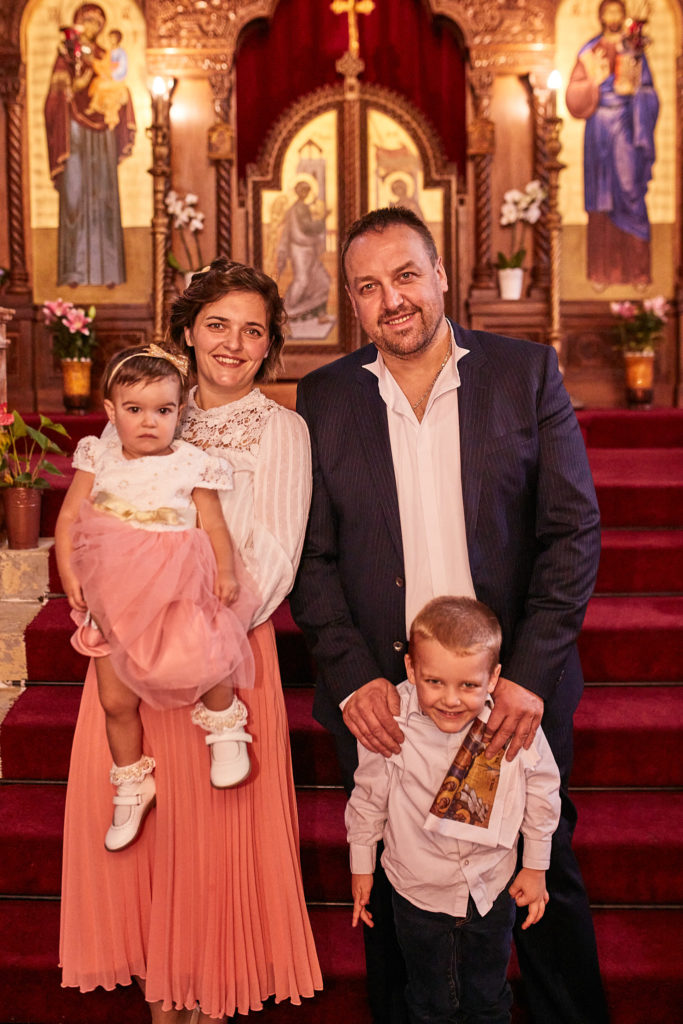 Family of four standing on the red-carpeted steps in front of the icon screen