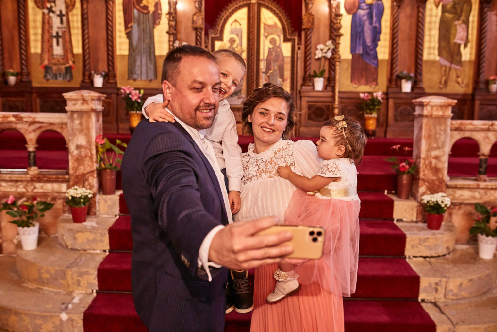 Father taking a selfie with his family on the church steps after the baptism