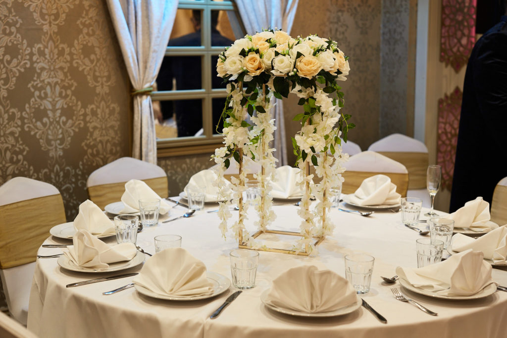 Table set for the mehndi with folded napkins and a centrepiece of white roses