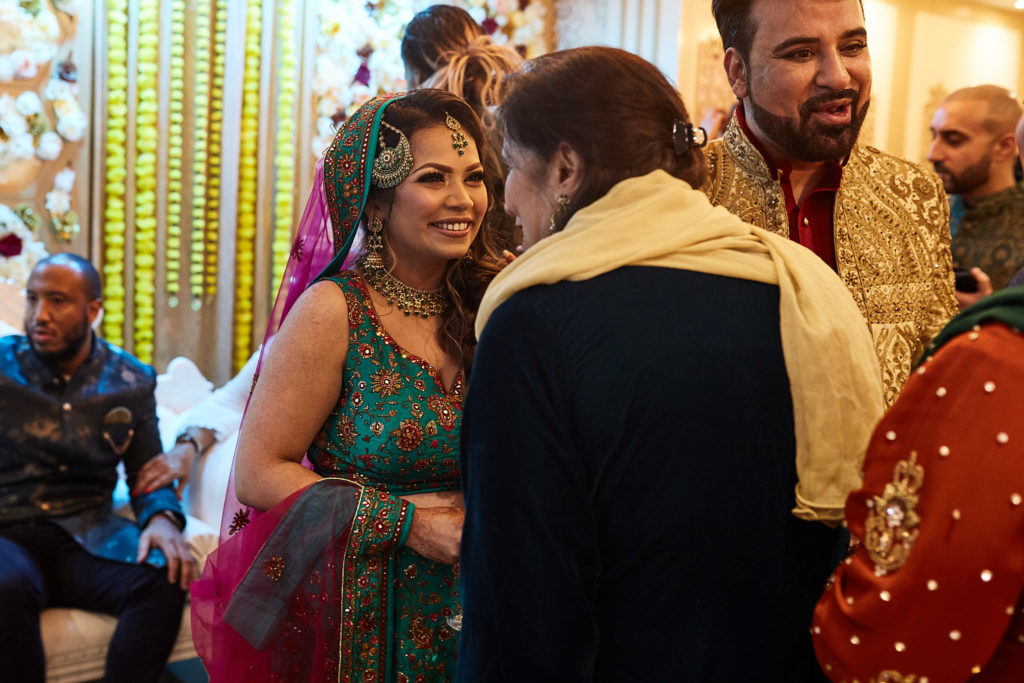 Bride-to-be in a green lehenga chatting with guests