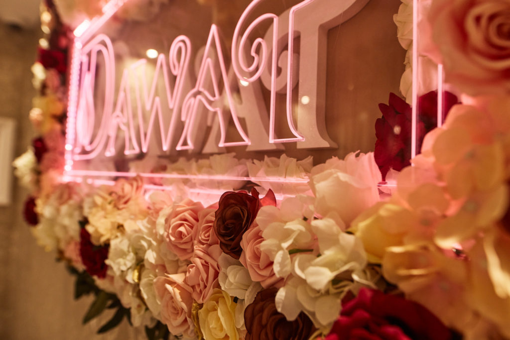 Neon sign surrounded by pink and white flowers