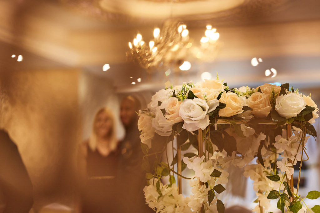 Flower arrangement on a table beneath a chandelier