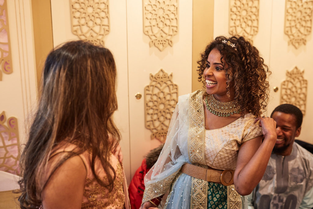 Guests in pastel lehengas chatting at the mehndi