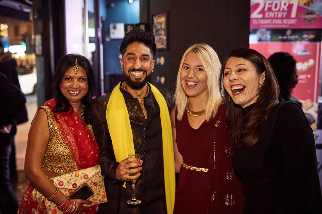 Four guests smiling together outside the venue in the evening