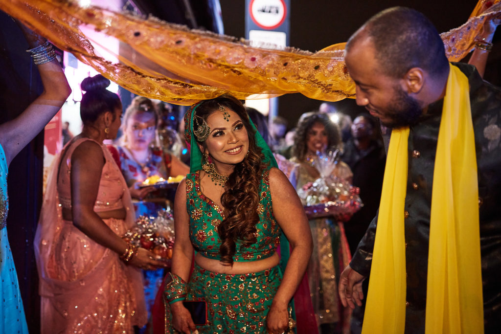 Groom-to-be in a yellow scarf bowing to the bride beneath the canopy