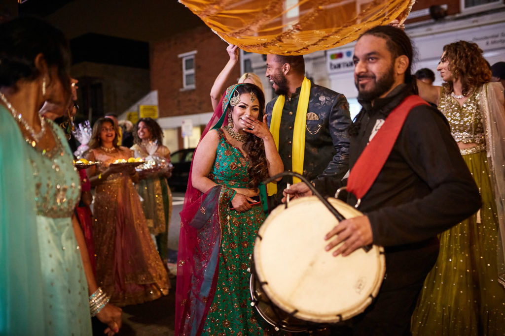 Dhol drummer leading the mehndi procession along the street
