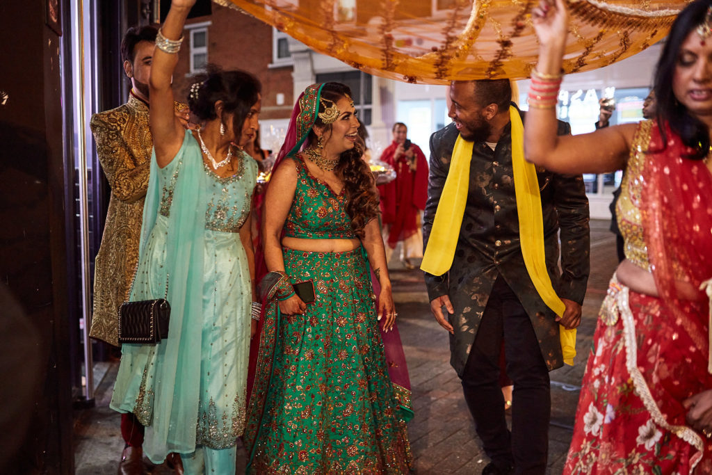 Bride and groom walking under the canopy with their guests around them
