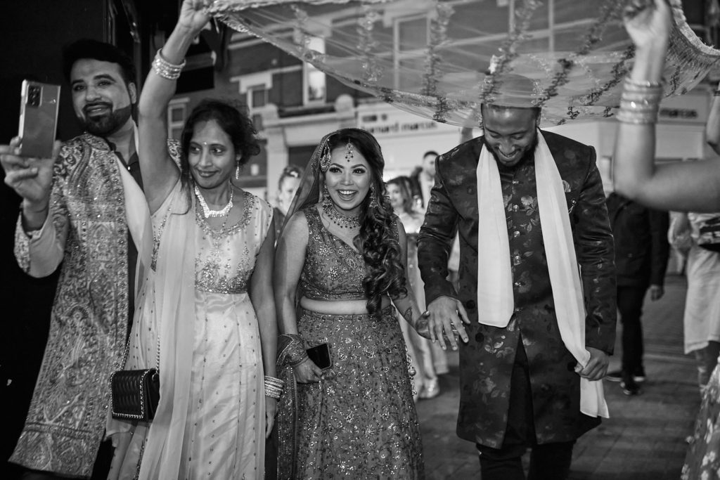Black and white photo of guests clapping as the couple arrive in procession