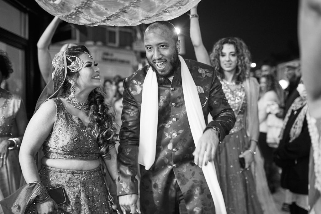 Black and white photo of the bride and groom dancing along the street under the canopy