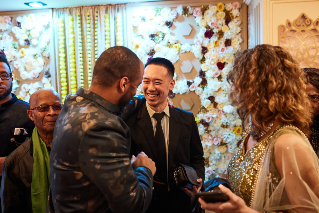 Guests chatting in front of the flower wall