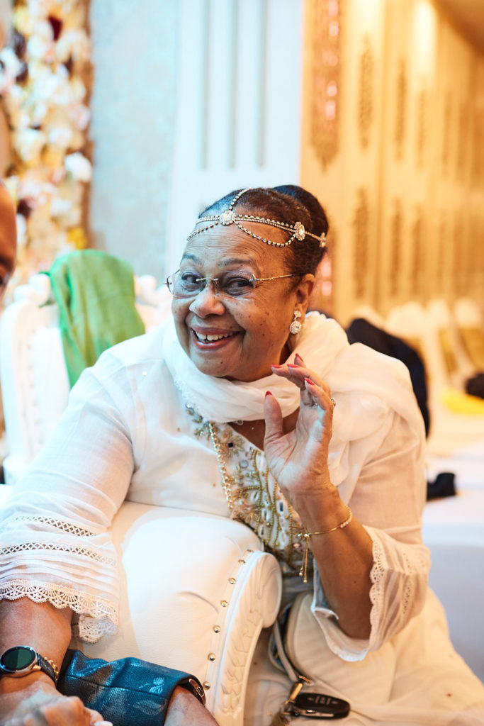 Older guest in white laughing as she sits on a white sofa