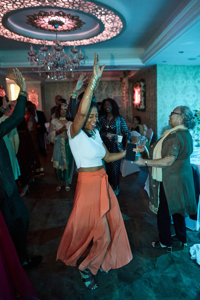 Guest in an orange skirt dancing with her arms in the air