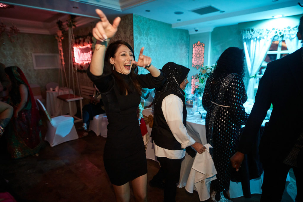 Guest in a black dress dancing with her arm in the air