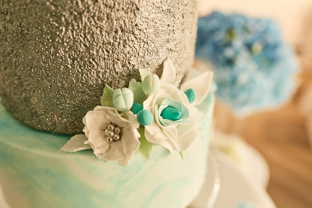 Close-up of sugar flowers on a turquoise and silver birthday cake