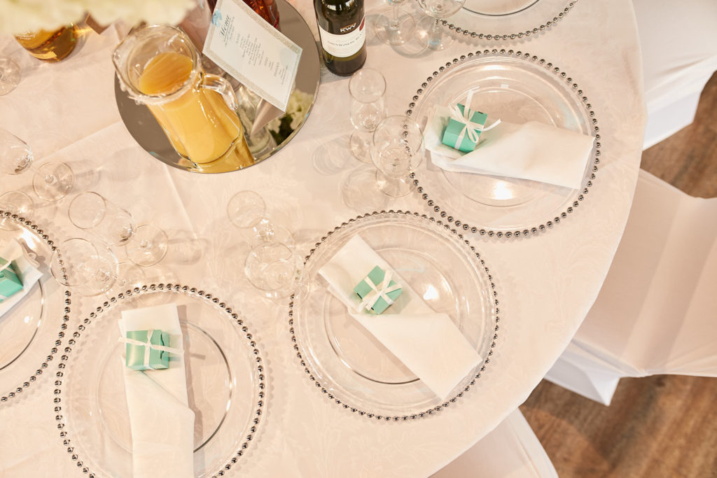 Round table set with beaded chargers and turquoise favours, seen from above