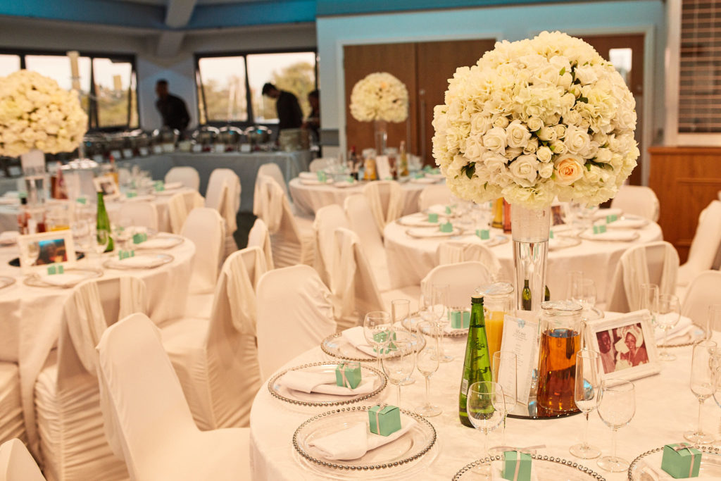 Function room set with white chair covers and rose centrepieces for a 60th birthday party at Fairlop Waters