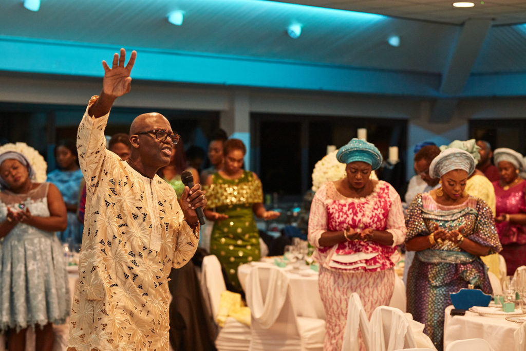 Guest raising his arm as others stand to applaud