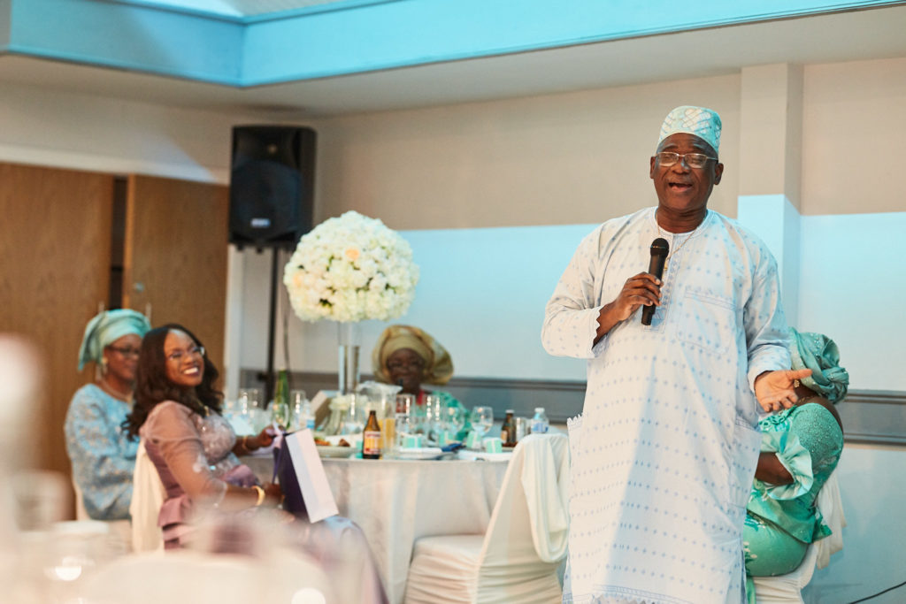 Man in white traditional dress giving a speech with a microphone