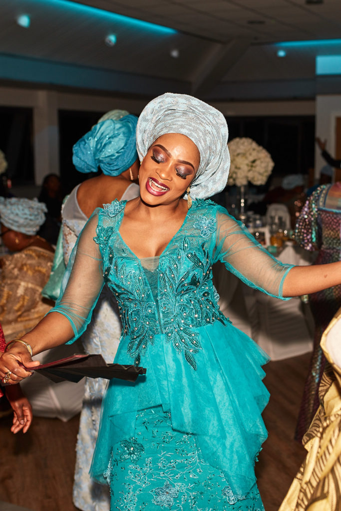 Guest of honour dancing in a turquoise lace outfit and silver head tie