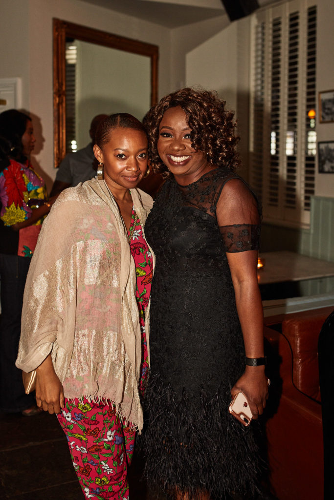 Birthday host in a black lace dress smiling with a guest