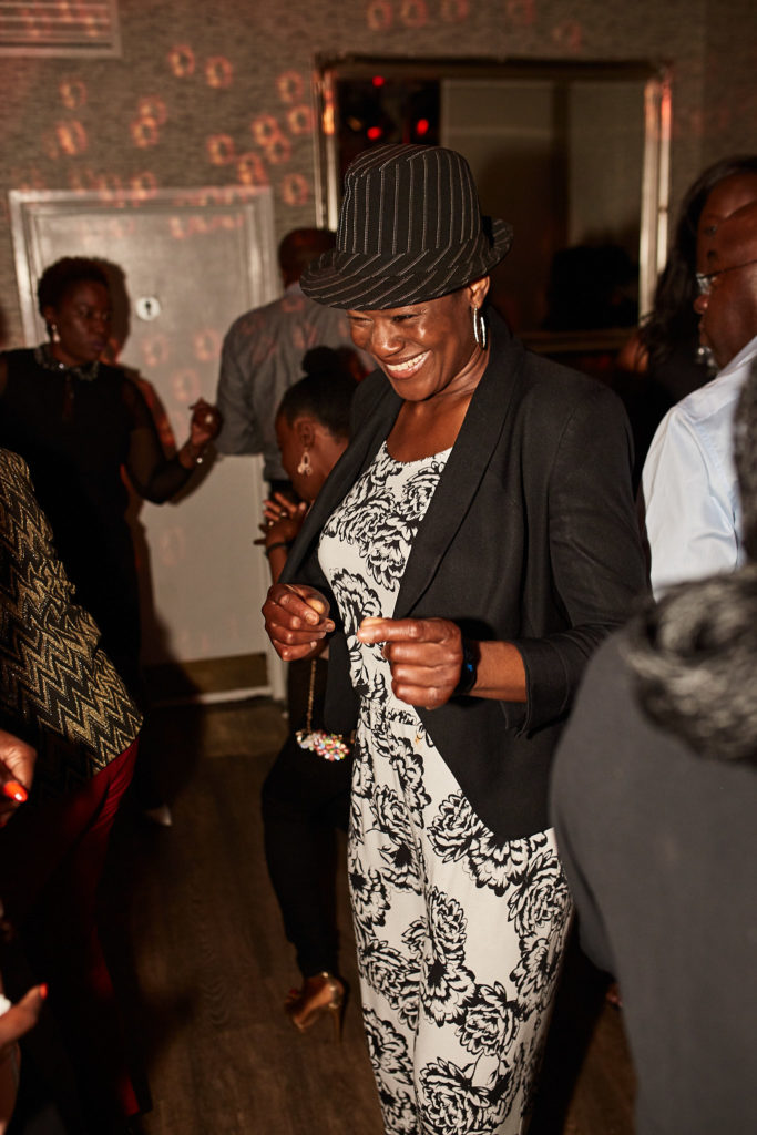 Guest in a trilby hat and patterned dress dancing