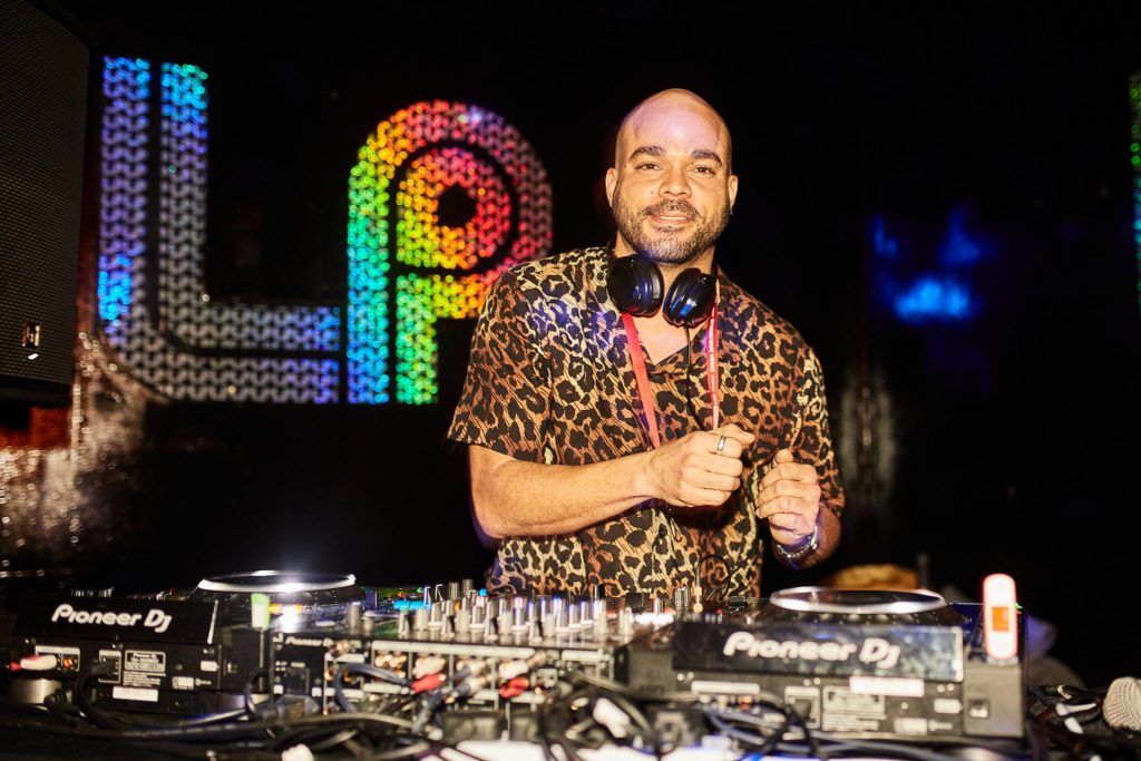 DJ in a leopard print shirt smiling behind the decks at a charity night at The Curtain Club, London