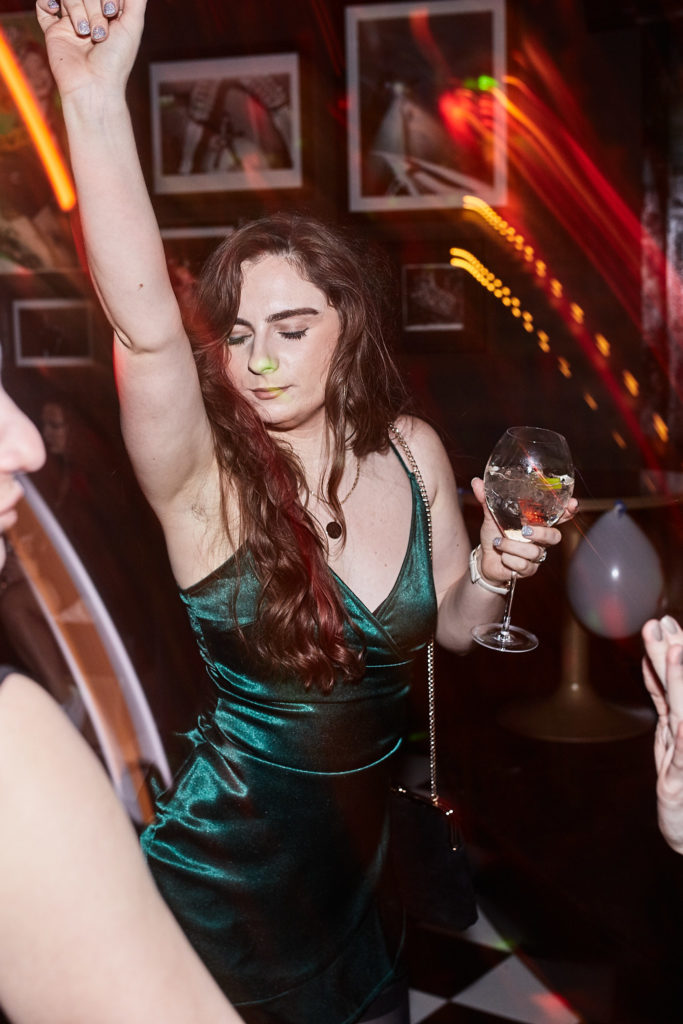 Guest in a green satin dress dancing with a drink in her hand