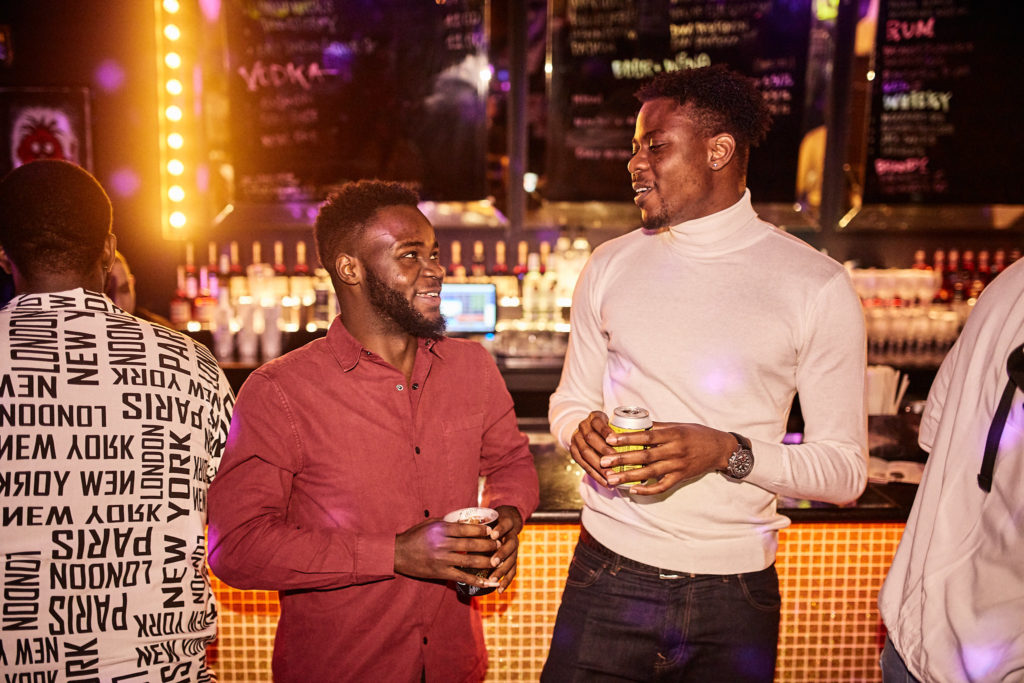 Two guests with drinks chatting in front of the bar