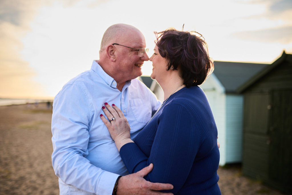 Engaged couple about to kiss beside the beach huts on Mersea Island