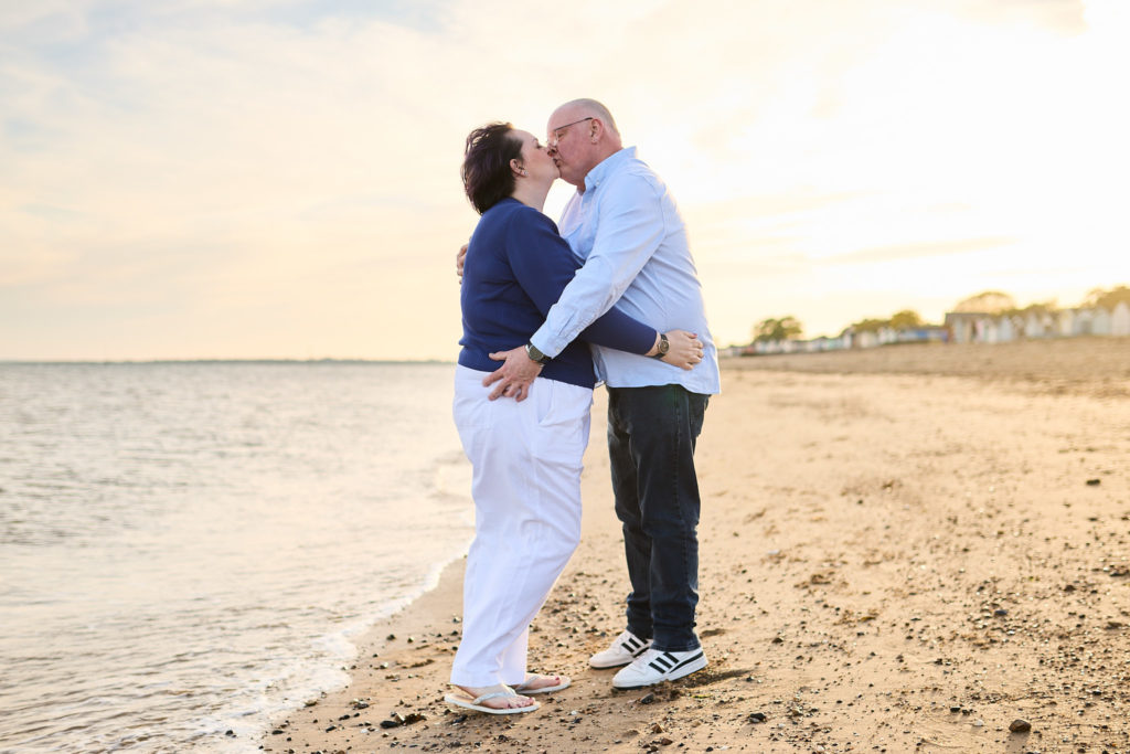 Engaged couple kissing at the water's edge on a beach engagement shoot at Mersea Island
