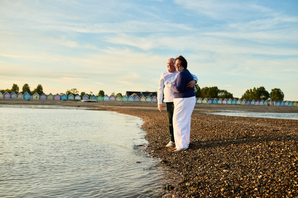 Engaged couple standing together at the water's edge at dusk