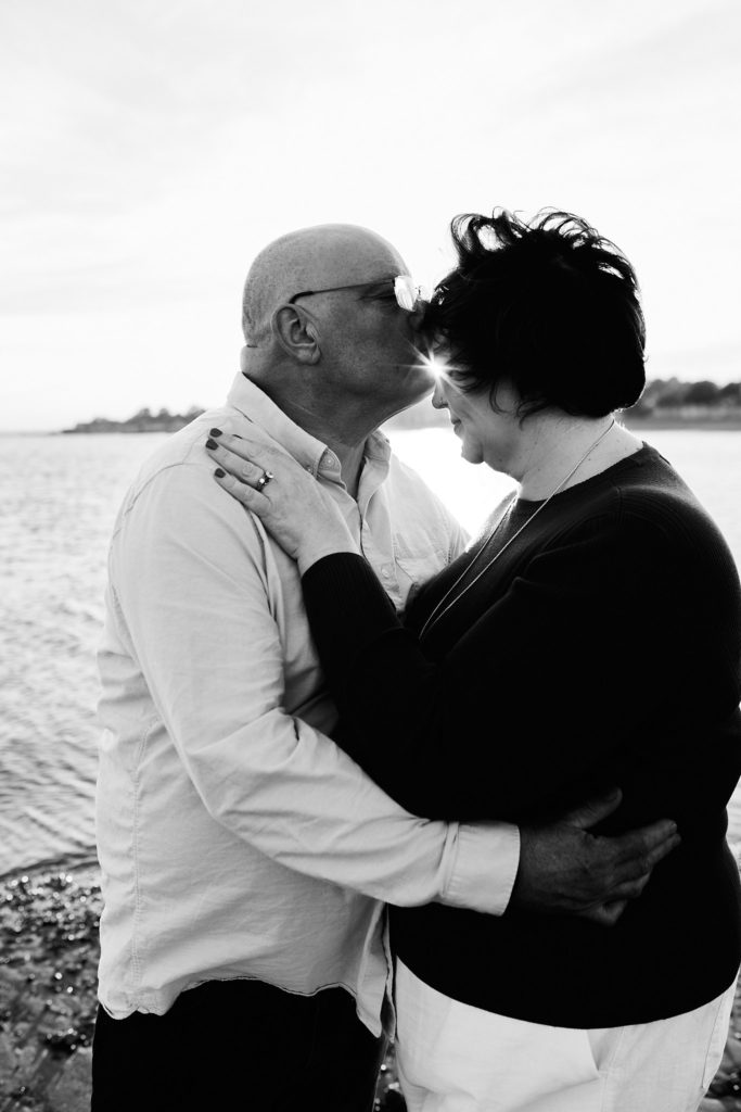 Black and white photo of an engaged couple embracing on the beach