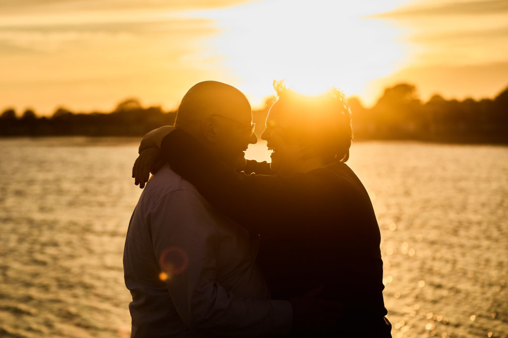 Engaged couple in silhouette against the setting sun on Mersea Island, Essex