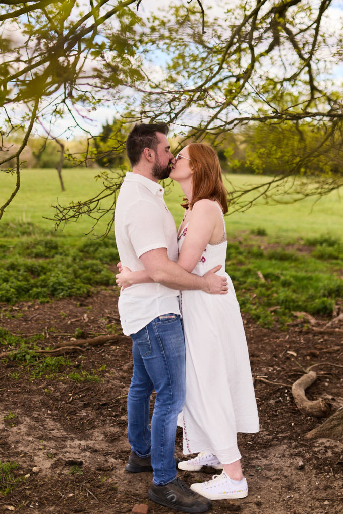 Engaged couple kissing under a tree on their countryside engagement shoot in Essex
