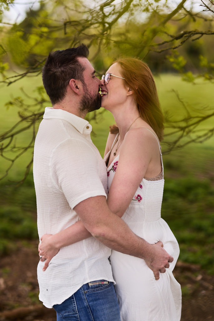 Engaged couple laughing nose to nose in the Essex countryside