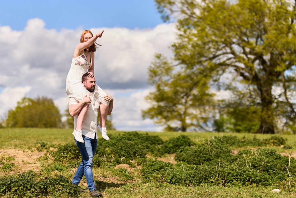 Man carrying his fiancée on his shoulders across a field