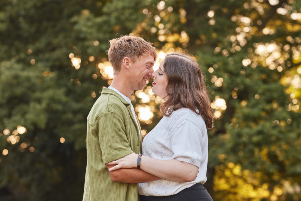 Engaged couple laughing nose to nose in golden sunset light