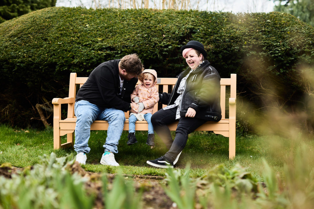 Couple sitting on a park bench with their toddler between them