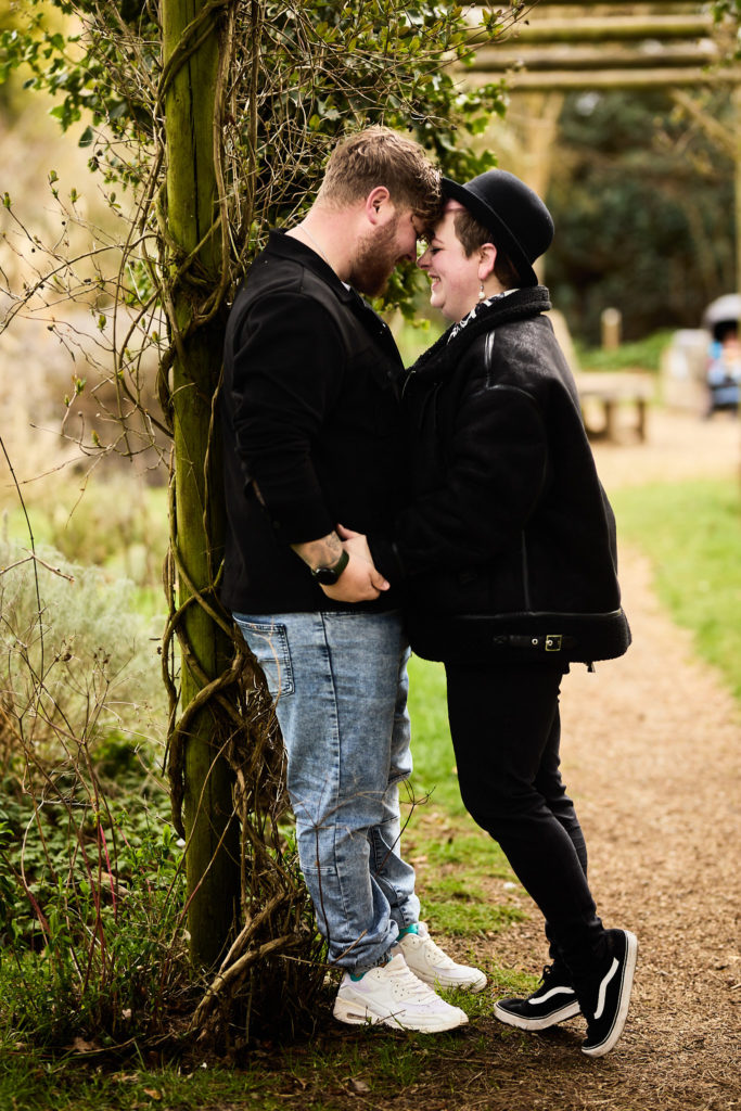 Engaged couple forehead to forehead on a park path on their engagement shoot in Braintree, Essex