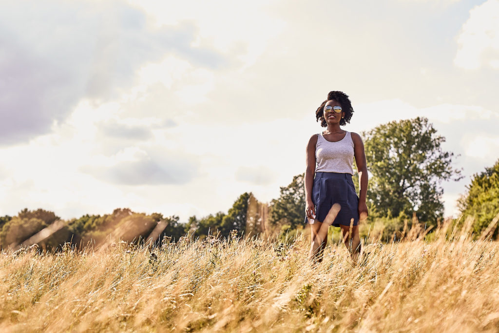 Woman walking through long grass on Hampstead Heath under a cloudy sky