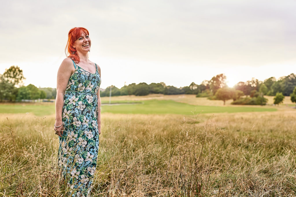 Woman with red hair looking across the meadow on Hampstead Heath
