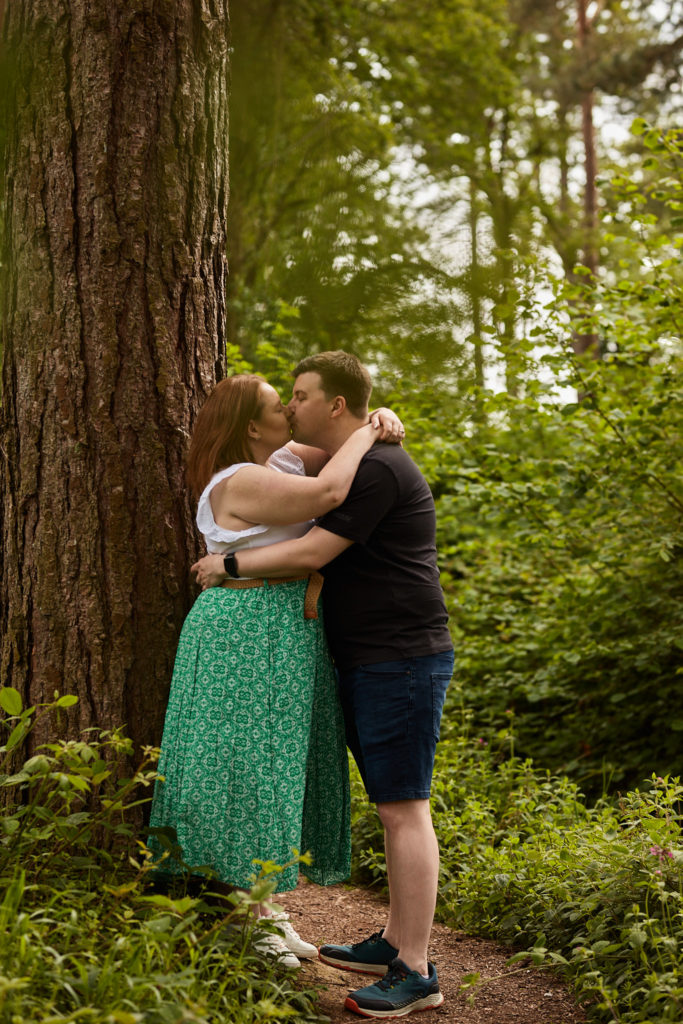 Engaged couple hugging on a woodland path