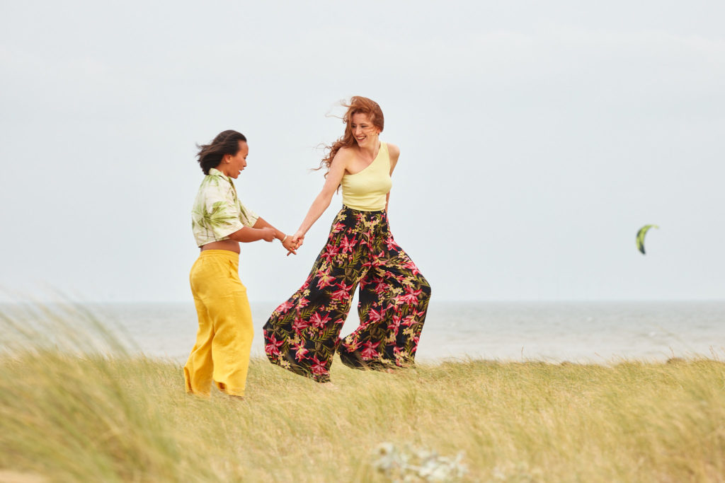 Engaged couple dancing in the dunes with the sea behind them